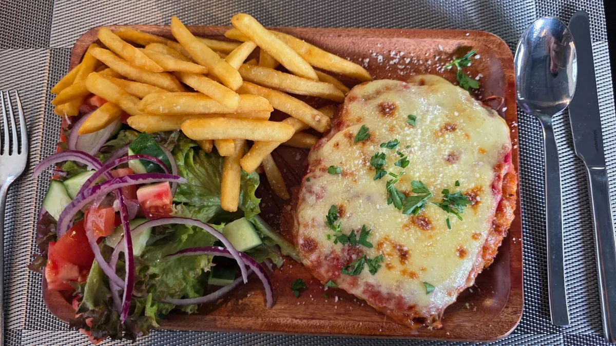 Chicken parmi topped with melted cheese, served with fries and salad at The Social